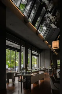 Elegant dining space with wooden furniture, potted plants, and wine glasses on tables