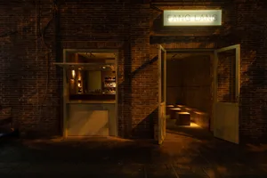 Cozy Asian restaurant with a brick wall, wooden door, and bottles on display, blending modern and traditional design elements