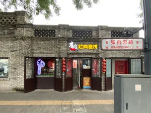 A warm and inviting Asian restaurant with a brick exterior, wooden doors, and red accents, featuring tables and chairs arranged in a comfortable dining atmosphere