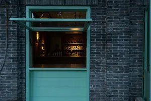 A casual bar interior with a wooden counter, bottles, and scattered cups, set in a warm and inviting atmosphere