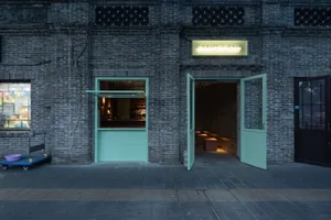 A welcoming bar area with a green door, chairs, and scattered bottles, set in a relaxed atmosphere