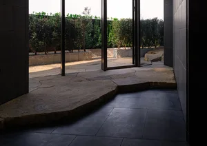 Well-lit modern interior space with stone flooring, a large window, and two doorways