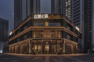 Modern Asian building exterior at night with a large sign on its facade, set against a cityscape