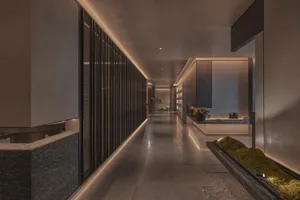 A luxurious hotel lobby with wooden panelled walls, large windows, and potted plants, creating a warm and inviting atmosphere