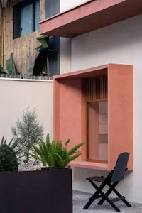 Cozy living space with a pink accent wall, a window, two chairs, a dining table, and several potted plants