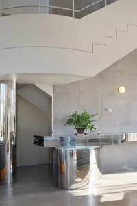 A modern metal staircase with a potted plant on the landing, set in a clean and well-maintained space with good lighting