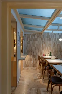 Inviting dining space with wooden accents, tables, chairs, and a bar counter, surrounded by bottles and warm lighting