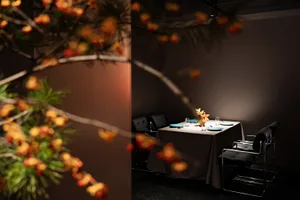 A well-lit dining area with a long table and multiple chairs, some with backs, surrounded by place settings and warm atmosphere