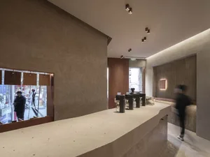 A casual cafe interior with a counter area, wooden accents, and a person walking past, serving beverages to customers