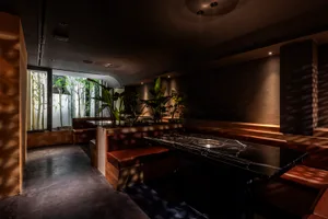 Warm and inviting restaurant interior with wooden benches, potted plants, and ample seating for guests
