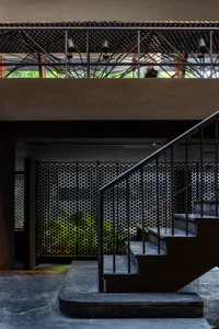 A minimalist building with two sets of metal staircases, one on each side, leading to a second floor, with natural light illuminating the space