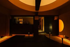A cozy bar with a circular dining area, surrounded by chairs and bottles, creating a warm and inviting atmosphere for socializing and enjoying food or drinks