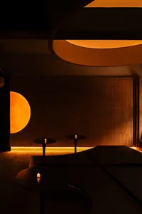 A cozy restaurant with a dining table surrounded by chairs, candles, and modern tile walls