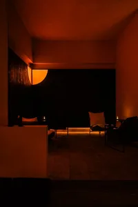 Cozy restaurant space with an orange-lit room, black walls, and a dining table with chairs and decorative items