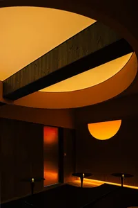 A modern interior space with a circular window, concrete walls, and a minimalist aesthetic