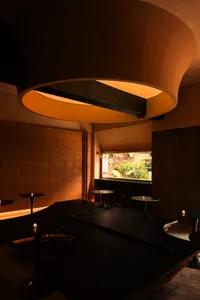 Modern restaurant interior with wooden paneling, tables, chairs, and potted plants, creating a warm and inviting atmosphere