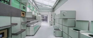 Industrial kitchen with green walls and floors, featuring various appliances and bowls for food preparation in a clean and organized space