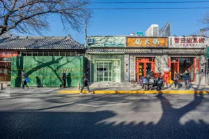A bustling Asian restaurant on a city street corner with a red building and green accents, surrounded by pedestrians and motorcycles