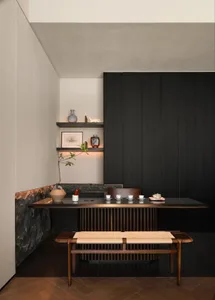 A darkened dining space with a wooden table surrounded by chairs, vases, and cups, creating a cozy and inviting atmosphere