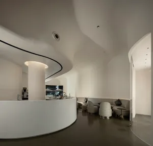 Modern restaurant interior with curved wall, seating areas, dining tables, and potted plants