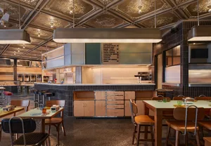 A modern restaurant dining area with a countertop, chairs, and dining tables, featuring a functional and welcoming atmosphere