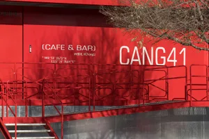 A red building with a staircase leading to a second floor, featuring railings and a possible restaurant or bar design