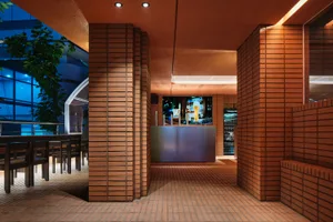 Warm and inviting bar interior with a brick wall, tile floor, chairs, and a mounted TV