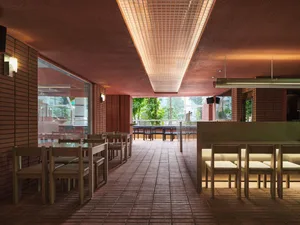 A well-lit restaurant with brick walls, red ceiling, and dining tables and chairs, creating a warm and inviting atmosphere