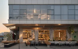 A cozy restaurant dining area with multiple tables, chairs, and potted plants, creating a welcoming atmosphere