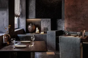 Warm and inviting restaurant interior with wooden tables, chairs, and a kitchen in the background