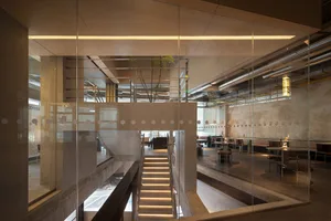 Open modern space with a glass wall, wood flooring, and natural light, featuring a dining table and multiple chairs