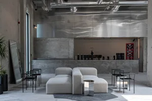 Open living area with a large couch, two chairs, and white walls, giving it a clean and minimalist look