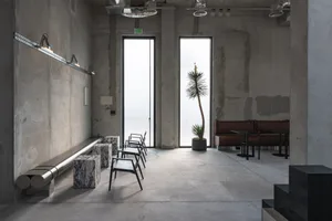 A bright and inviting room with a large window, chairs, and a potted plant, filled with natural light