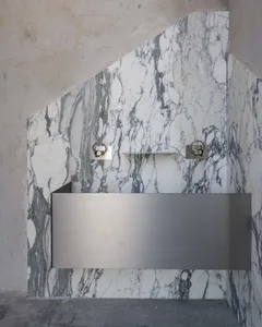 Luxurious marble bathroom with a metal sink, large mirror, and warm lighting