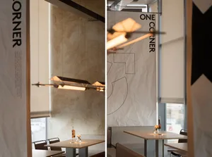 Dimly lit modern restaurant space with a dining area and kitchen featuring wood and glass materials