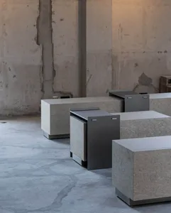 A concrete room with four gray metal tables made of stainless steel, arranged in a row, in a minimalist and functional setting