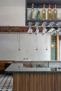 Elegant restaurant bar with a wooden countertop, wine glasses, and scattered cups, set in a sophisticated atmosphere