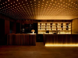 A sophisticated bar area with a long counter featuring wine glasses and bottles, surrounded by modern wood and metal elements