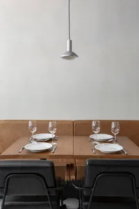 Elegant dining area with brown leather chairs, multiple tables set with wine glasses, plates, and cutlery, creating a sophisticated ambiance