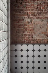 A bathroom with a brick wall and a black and white checkered floor, creating a unique and visually appealing atmosphere
