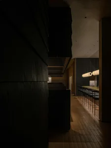 A small restaurant with a dark atmosphere, featuring chairs placed throughout the space, with a focus on functionality in the seating arrangements