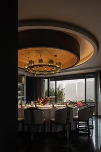 Sophisticated dining space with a round table, wine glasses, and wood and metal elements, set against a refined backdrop