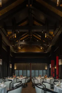 Ornate dining hall with high ceilings, wooden beams, and intricate designs, featuring a large dining table and well-lit space