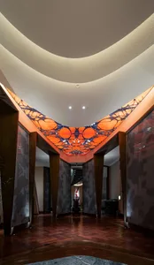 A modern interior space with a striking orange and red geometric design on the ceiling, creating a vibrant and energetic atmosphere