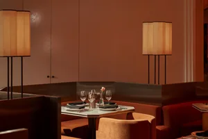 Dining area with a table, chairs, wine glasses, and a vase, surrounded by warm red-hued walls