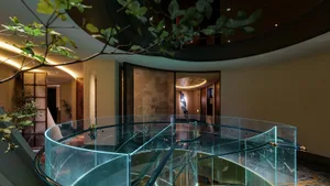 A modern staircase with a glass railing in a well-lit, elegantly designed space with clean lines and minimalistic elements