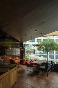 Modern restaurant interior with a dining area, bar, and potted plants, featuring clean lines and minimalistic design elements, with dim lighting creating a cozy atmosphere