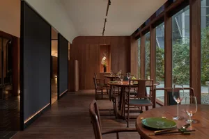 Warm and inviting dining space with wooden floors and walls, featuring a large dining table and chairs, wine glasses, and a cozy atmosphere