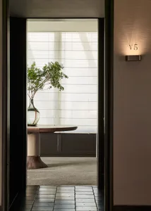 A well-lit room with a wooden table, a potted plant, and a doorway, possibly with natural sunlight coming through the window