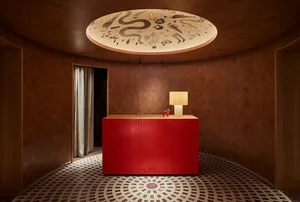 A modern kitchen with a red countertop, wooden floors, and two lamps, creating a warm atmosphere with clean lines and minimalistic decoration